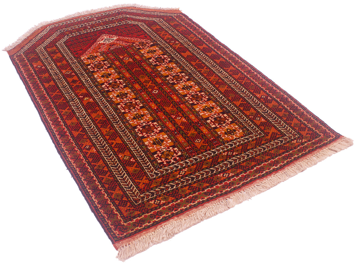 A rectangular Turkoman prayer rug with a traditional geometric pattern in shades of red, orange, and brown, featuring cream-coloured fringe on two short ends, shown on a plain white background.