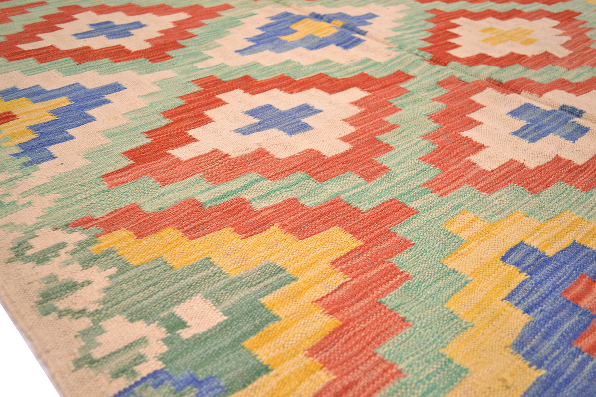 Handwoven kilim rug close-up showing diamond and cross motifs in warm orange and blue