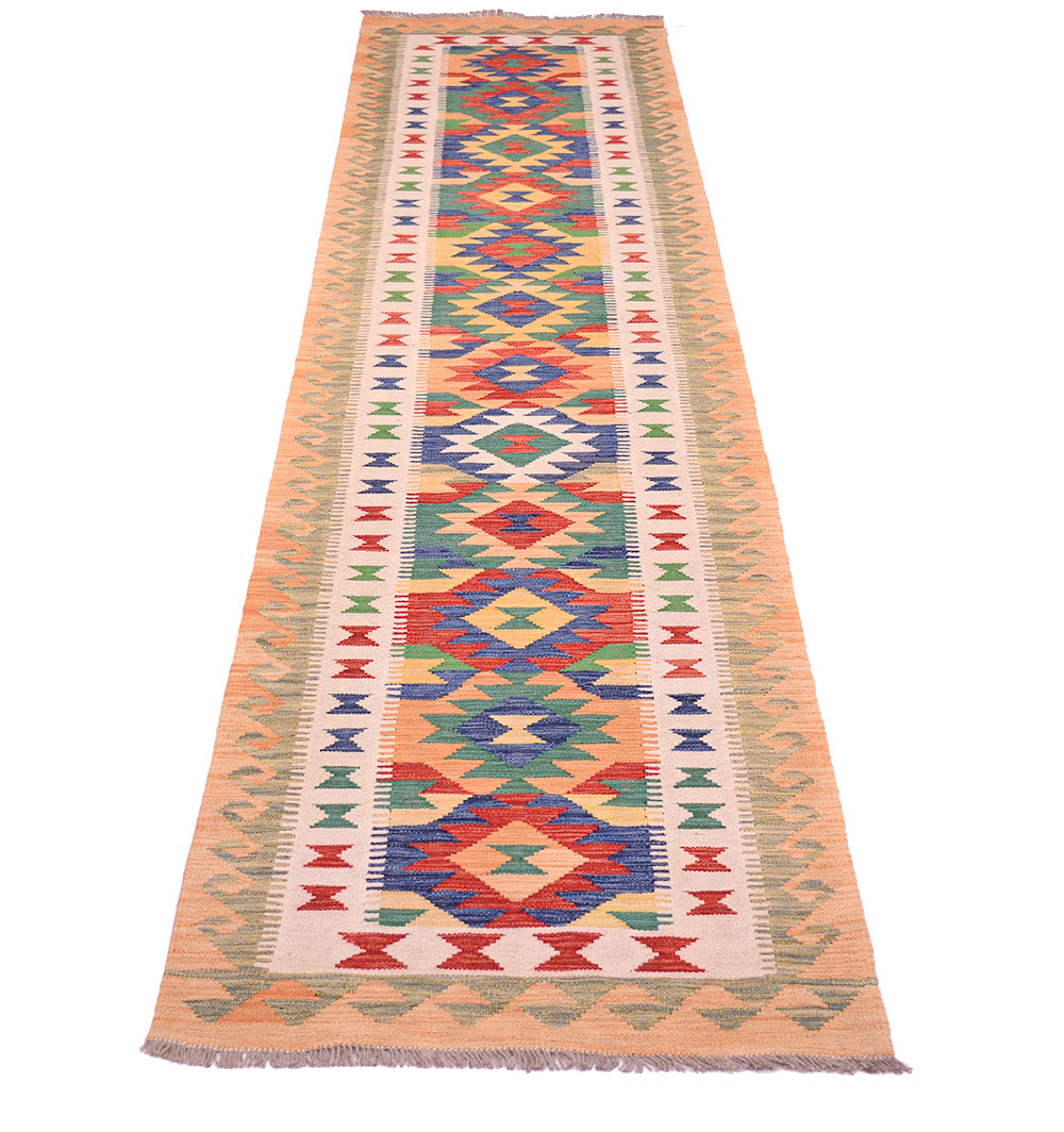 A long handwoven multicolour Kilim long runner rug with a vibrant geometric pattern in red, blue, green, and orange on a cream and peach background, shown flat against a white background.