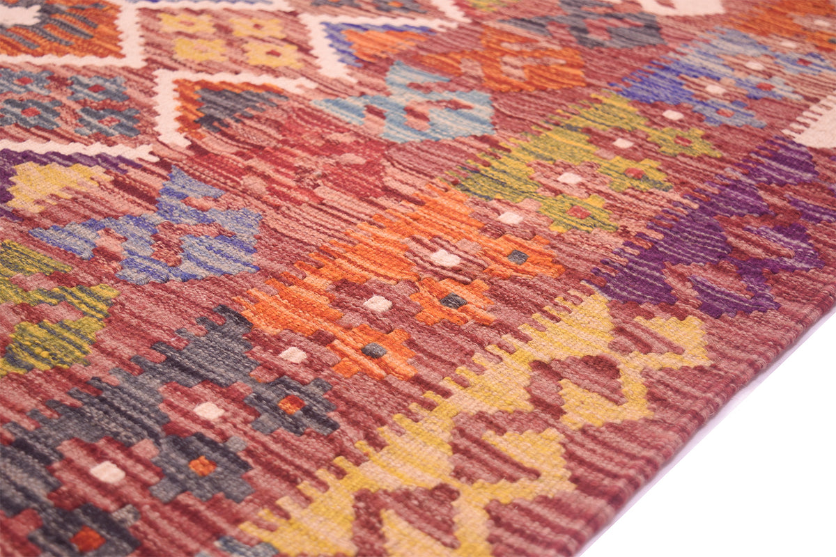 Handwoven kilim rug surface detail with orange, yellow, purple, and white weave.