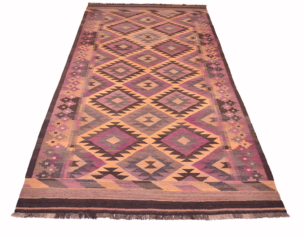 A rectangular handwoven vintage Afghan Kilim wide runner rug with a geometric diamond pattern in shades of pink, purple, brown, beige, and black, featuring fringe on the top and bottom edges.