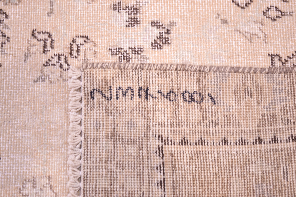 Reverse of cream blue and beige vintage carpet showing back of handknotting and cotton warp foundation and fringes. Shaven softened coloured zero pile detail.