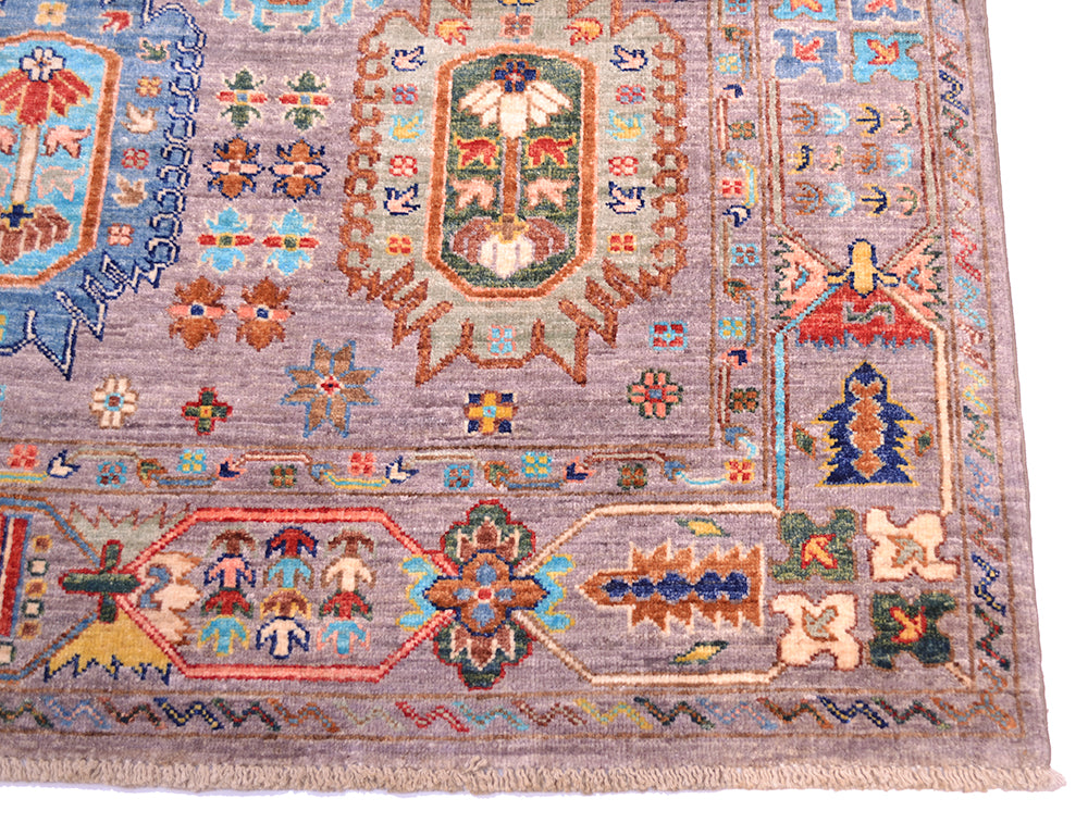 A close-up of a traditional hand-knotted Afghan area rug with a grey field, featuring a central floral medallion in green, red, and blue, surrounded by geometric borders in beige, orange, and blue.