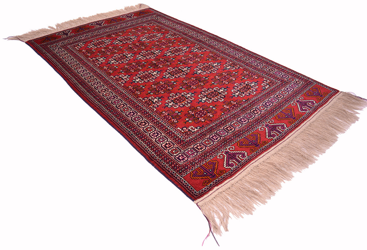 A traditional Turkoman-style Yamut area rug with a red field, dark navy and beige borders, and cream-coloured fringe on the ends, shown against a plain white background.