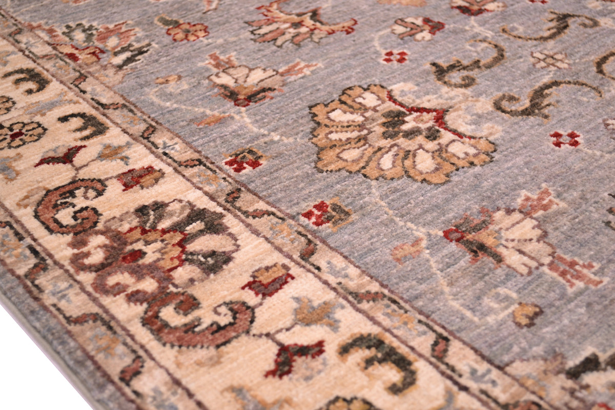 Detail of border of afghan rug with cream background and secondary colours of pinkish terracottas and olive browns