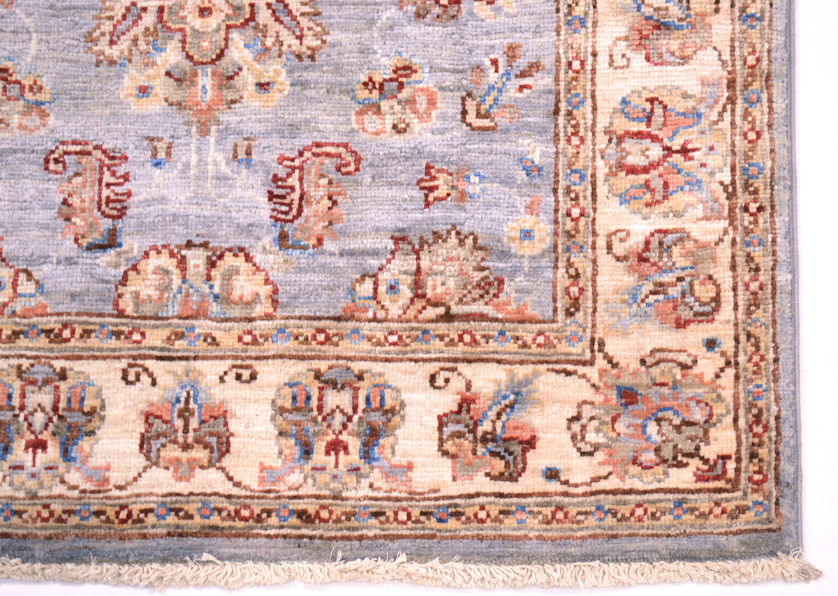 Details of border of soft coloured afghan ziegler runner with red and blue accents and outlines.