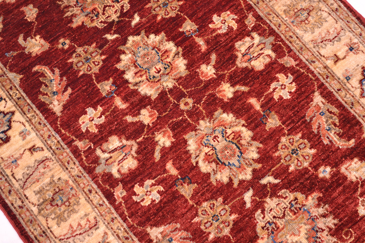 Close up of detail of main floral field of Ziegler design rug with rich red rust field and golden cream border with flowing blossom and vines.