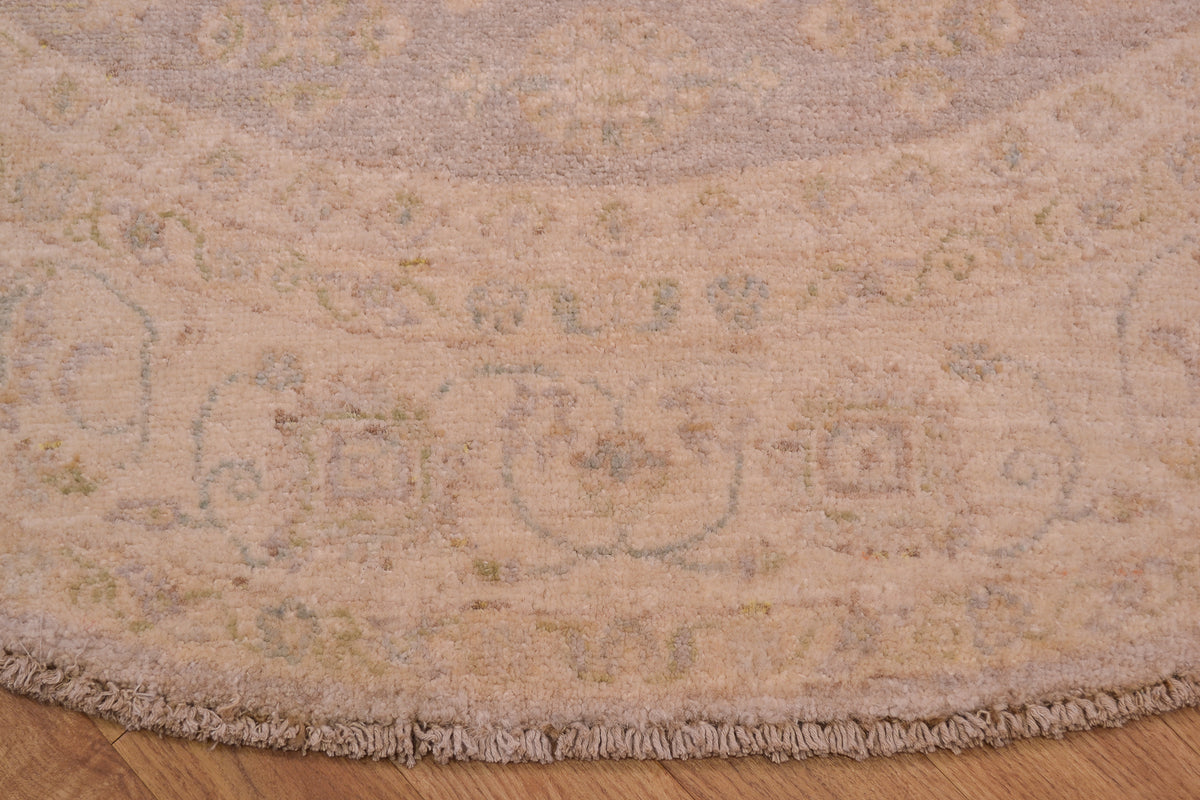 Detail of border of afghan ziegler circle rug with cream and beige background of border with floral motifs woven on cotton foundation.