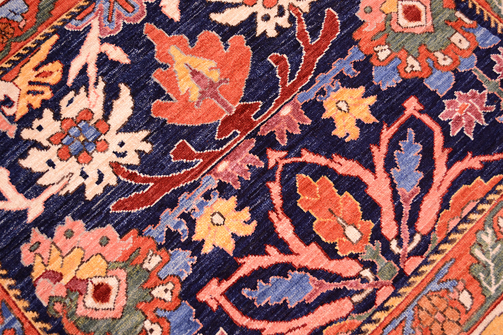Close-up of antique floral rug texture with navy and orange floral motifs and multicolor details.
