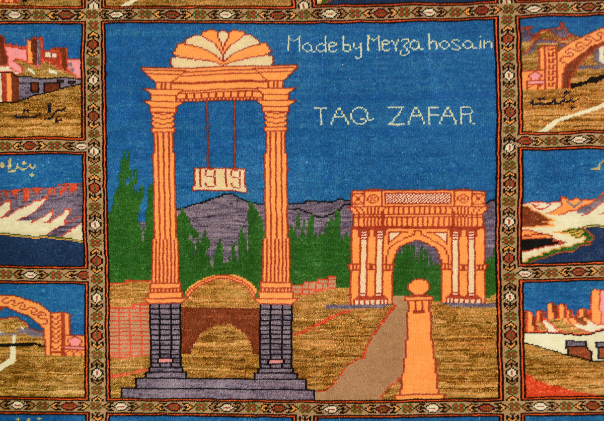 A fine silk and wool hand-knotted Pictorial Afghan rug or mat featuring a stylised architectural scene with large peach-coloured arches and pillars, blue sky-like background areas, green trees, and smaller inset scenes around the border. White text reads 'Made by Merza hosain' and 'TAQ ZAFAR'.