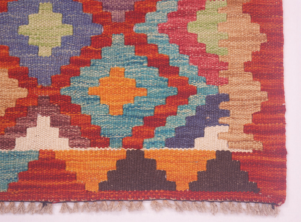 Close-up kilim rug with blue, red, cream and yellow flower-like star motifs