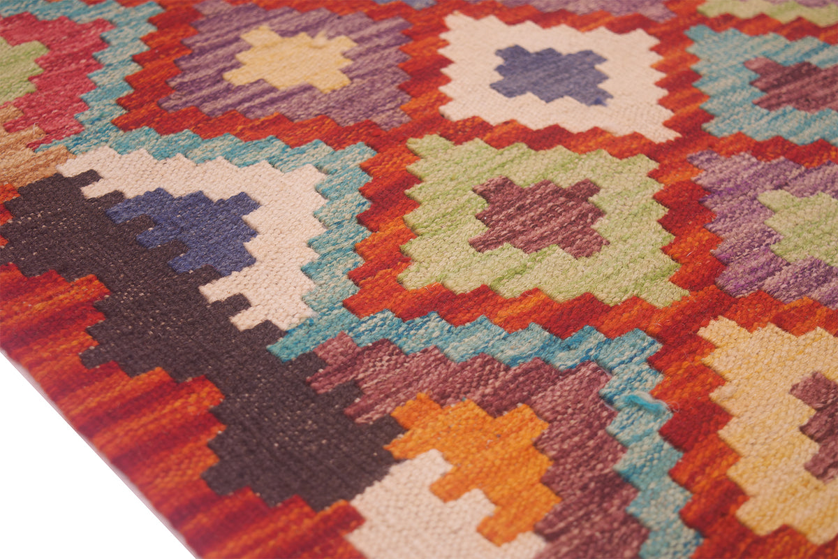Close-up kilim rug with orange, teal, cream and navy geometric blocks and crosses