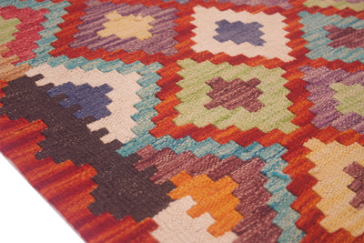 Close-up kilim rug with orange, teal, cream and navy geometric blocks and crosses