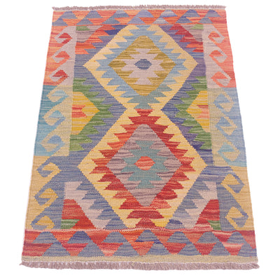 A small woven kilim rug with a colourful geometric diamond pattern, featuring fringed edges on a plain white background.