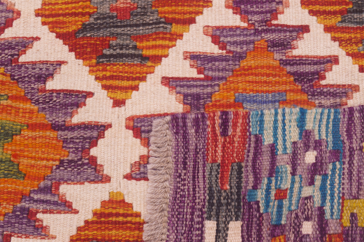 Kilim rug close-up with multicolor geometric pattern and short fringe at edge.