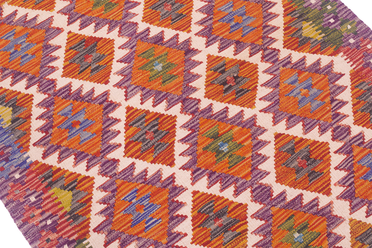 Kilim rug close-up: purple, orange, and white geometric squares and diamonds.