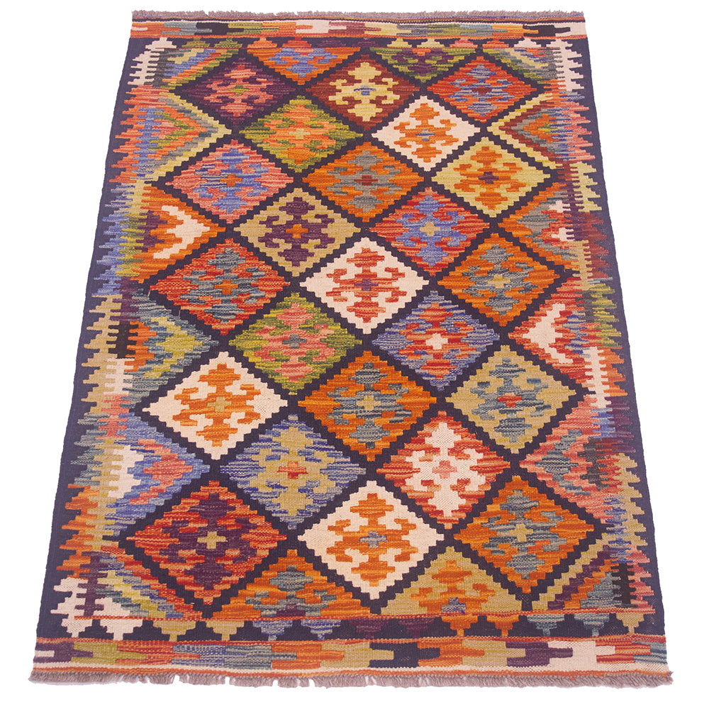 A kilim area rug with a vibrant geometric diamond pattern in orange, blue, beige, and purple