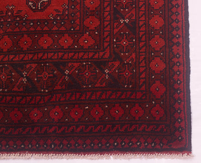 Close-up of a handmade red Afghan carpet with intricate designs and colours.