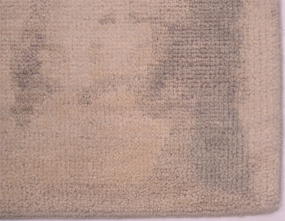 Detail of corner of handknotted carpet in soft greys and cream beiges.No fringes cotton warp threads neatly bound ends and sides