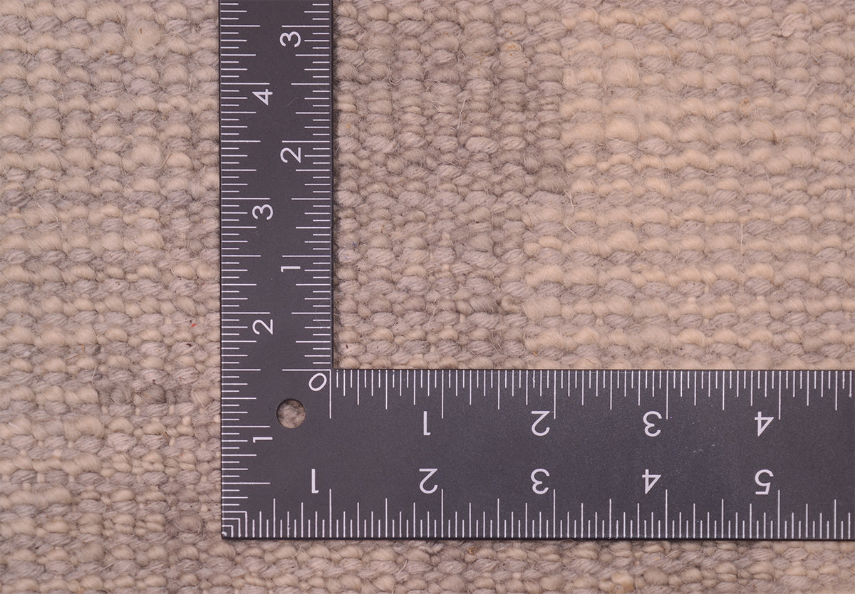 Reverse of carpet showing knotting on back of neutral toned  abstract modern carpet in greys and beiges and creams. 