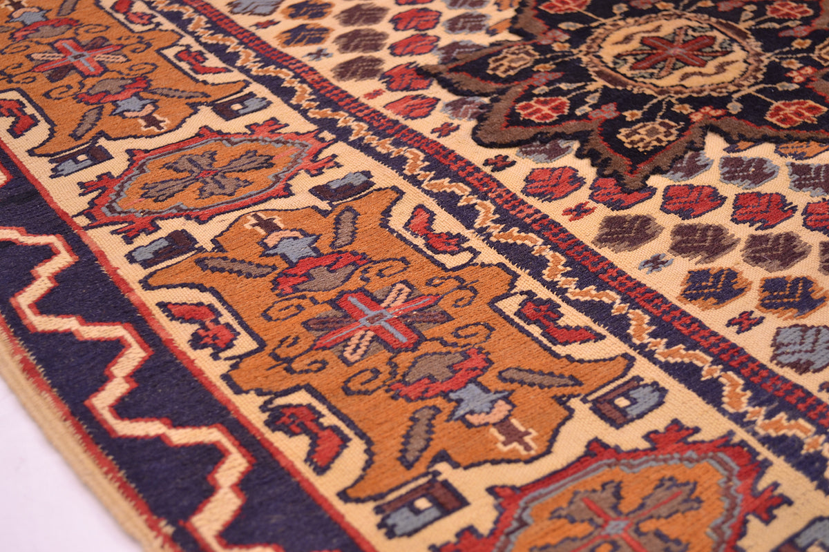A close-up of a traditional patterned Kilim Barjasta rug with a beige field, navy blue borders, and orange, red, and gray motifs.