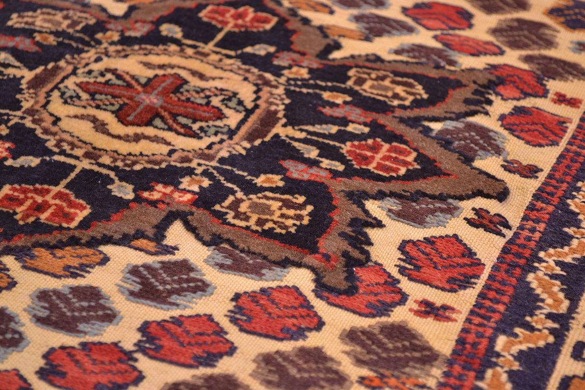 Close-up of an ornate patterned medallion from a Afghan Barjasta rug with a beige background and dark navy, rust red, and brown floral motifs.