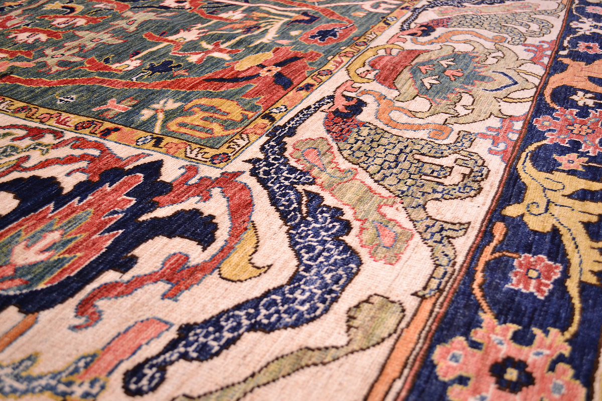 Detal of expansice semi abstracted flroal motifs of antique style carpet with pure wool pile with natural vegetable dyes. Detailing of flowing leaves of main border.