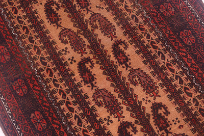 A close-up of a antique Baluchi prayer rug featuring diagonal bands with intricate geometric and paisley (boteh) motifs in dark red, black, and warm terracotta tones.
