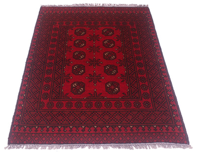 A traditional rectangular area red Afghan rug with a deep red field, dark navy and black geometric borders, and central bokhara motifs, finished with grey fringe on all sides.