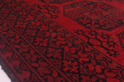 A close-up of a red and black Afghan Fil Pai rug, showing detailed woven motifs and borders.
