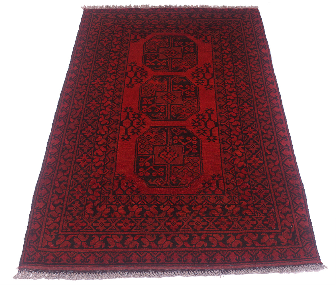 A rectangular red and black patterned Afghan Aqcha rug with fringed edges, photographed flat against a plain white background.