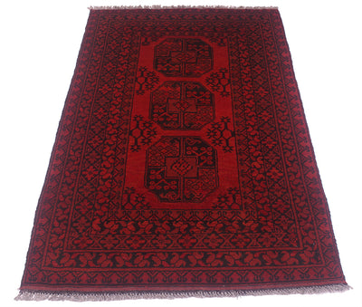 A rectangular red and black patterned Afghan Aqcha rug with fringed edges, photographed flat against a plain white background.