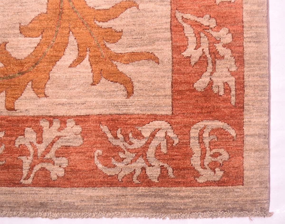 Corner of autunnal coloured handmade carpet with multiple leaf border in terracotta and grey-beige hues.