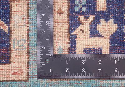 Close-up of the hand-knotted weave of a patterned Afghan Aryana rug with a dark metal ruler placed vertically and horizontally to show the scale of the weave and design.