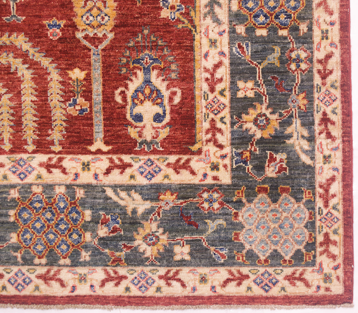 Close-up of a traditional patterned Pictorial fine Aryana Carpet corner showing a red field, green main boder, and cream narrow borders with floral motifs.