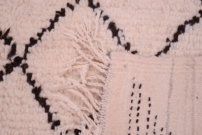 Azilal rug close-up of tassel and woven pattern, cream pile with black lines and soft pink.