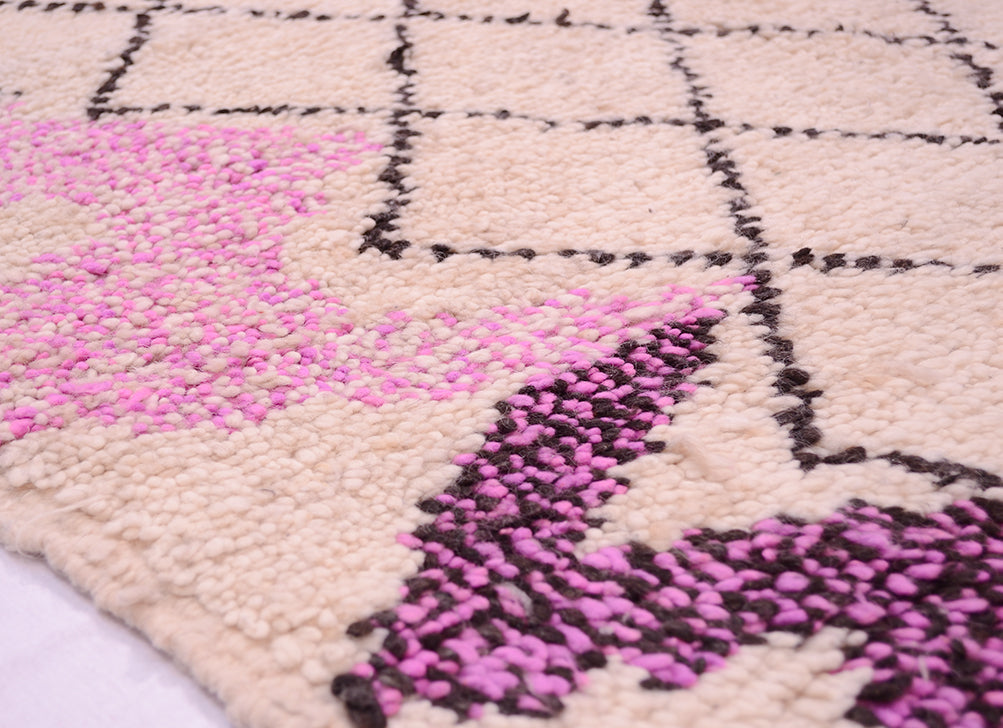 Rug corner detail with light pink pile, black accents, and magenta woven sections.