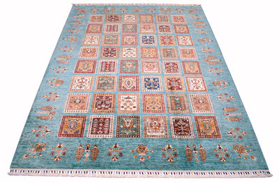 A 244x180cm rectangular Afghan Bakhtiari area rug with a turquoise blue field, featuring a grid of ornate square medallions in red, beige, and brown, finished with white fringe on two short ends.
