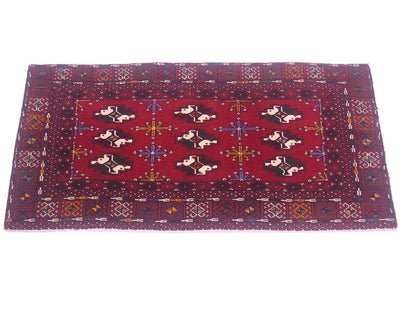 A rectangular red oriental Afghan Belouch small rug/mat with a geometric border and central field featuring stylised motifs in black, cream, blue, and orange, photographed flat against a white background.