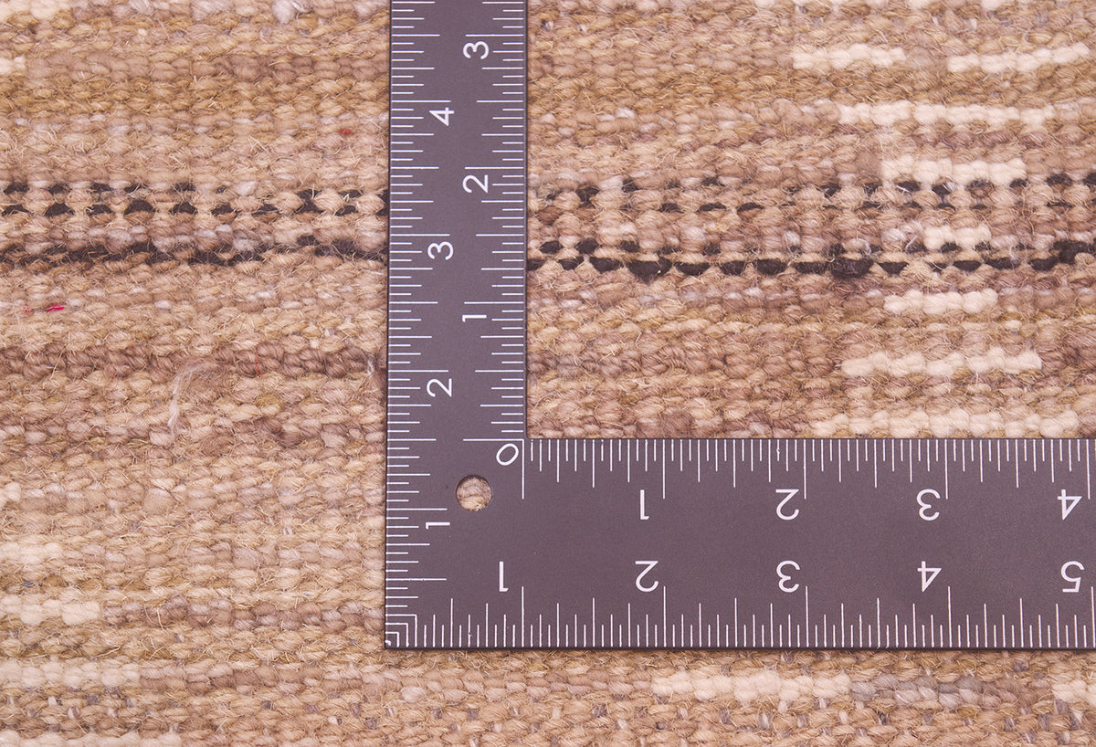 Close-up of back of a woven runner/rug  in beige and brown tones, shown with a metal L-square ruler to indicate scale