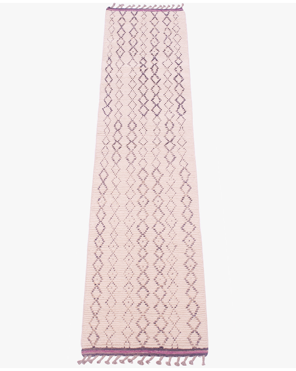 A long, narrow woven runner rug in cream with a repeating charcoal geometric diamond pattern and purple kilim ends with fringe at both ends, shown flat against a light gray background.