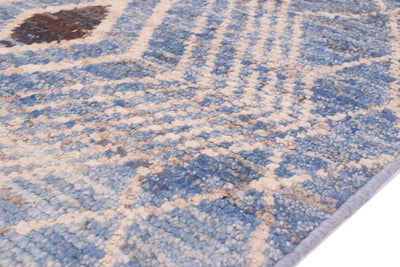 A close-up of a textured area rug/runner with a blue and cream geometric pattern, showing the pile texture and a light blue edge.