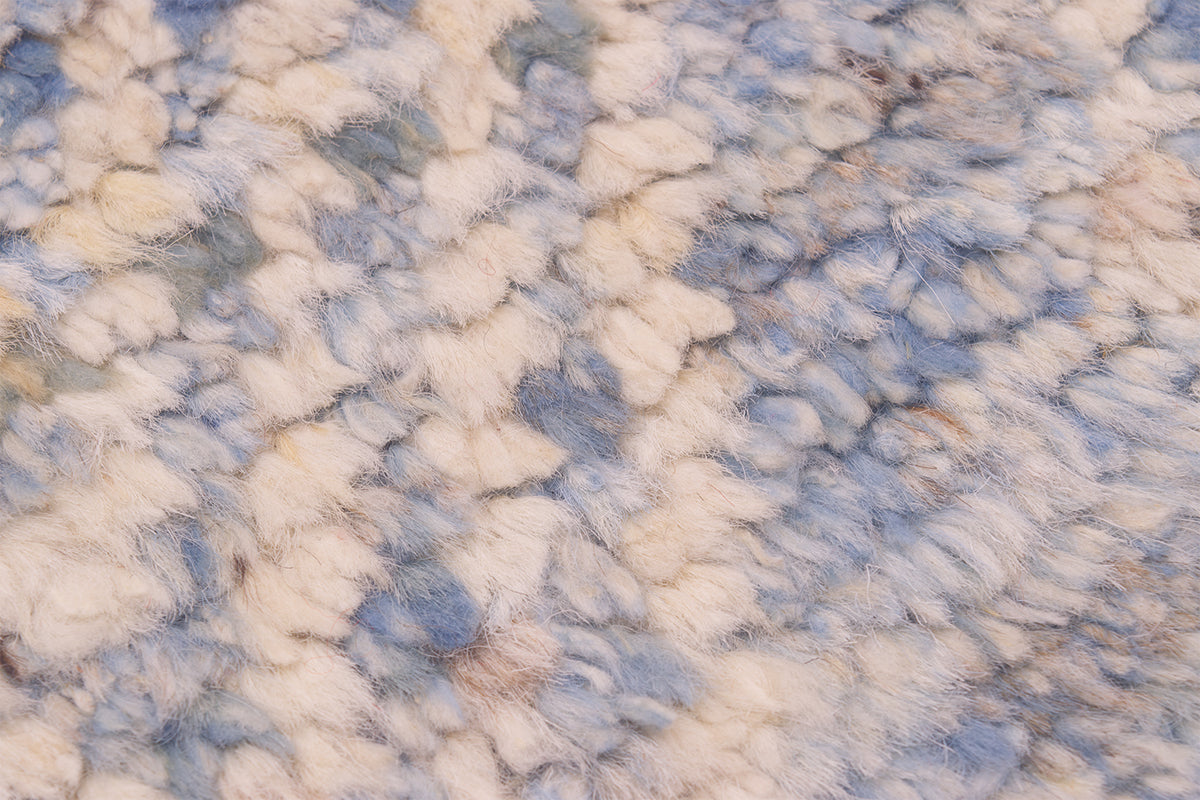 A close-up texture shot of a fluffy, shaggy rug/runner,  pattern in shades of cream, beige, and light blue
