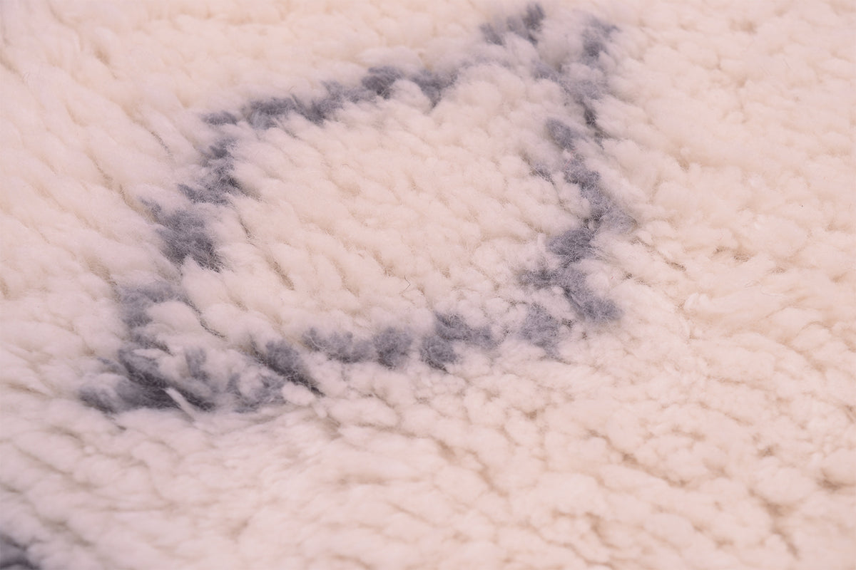 Close-up of a plush cream shaggy pile Berber style rug with a grey geometric pattern.