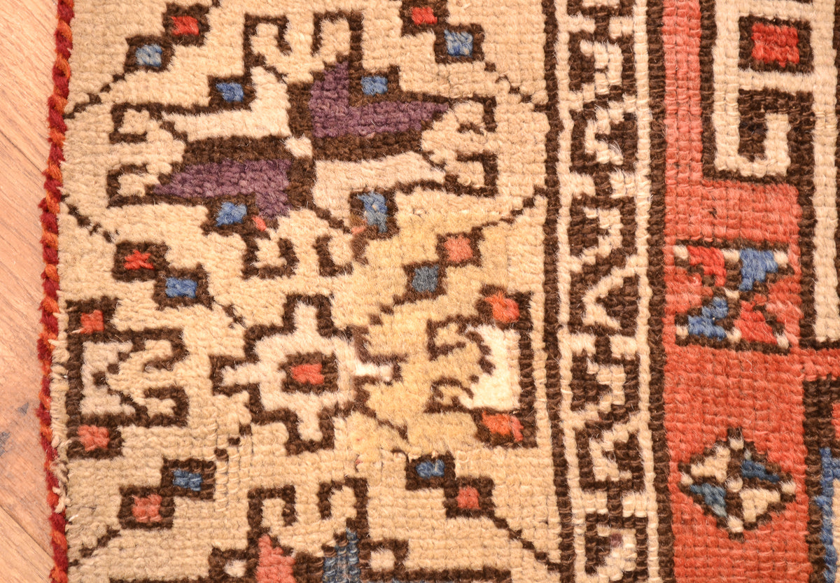 Antique geometric rug border close-up with orange, cream, and blue accents