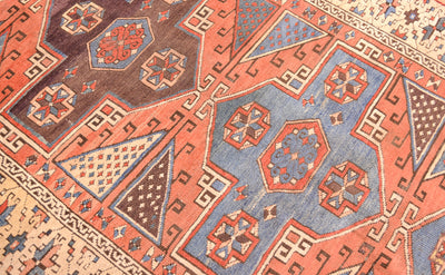 Close-up of Antique Bergama rug pattern with diamond motifs in blue, rust, and cream