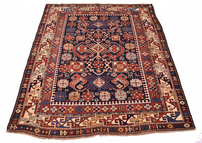 Antique rug with navy and red central panel, cream corner ornaments, detailed patterned frame.