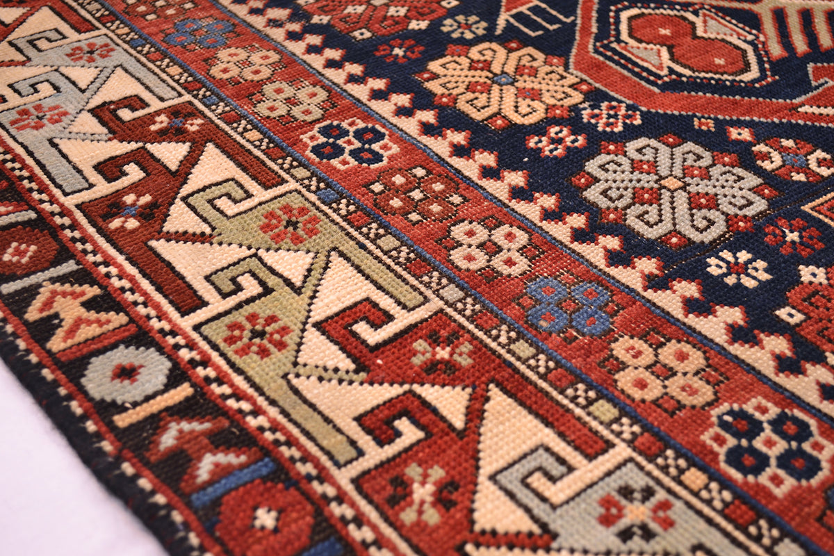 Rug border close-up with navy, rust, and cream geometric bands and repeating motifs.