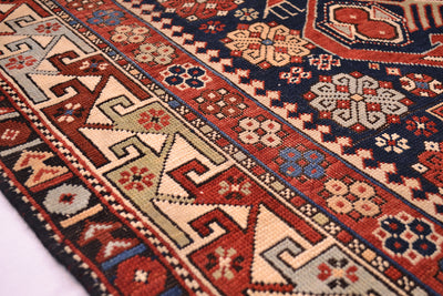 Rug border close-up with navy, rust, and cream geometric bands and repeating motifs.