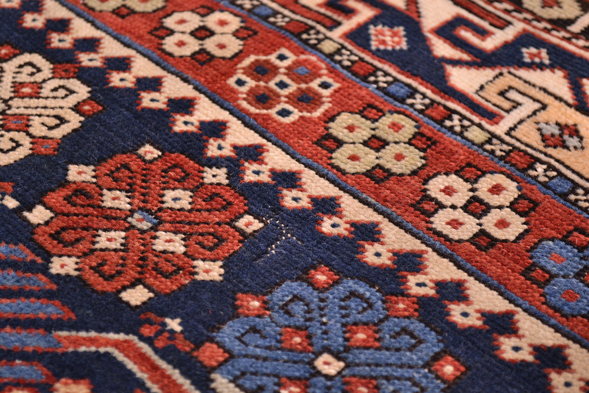 Rug close-up of floral medallions and corner designs in navy, red, and cream tones.